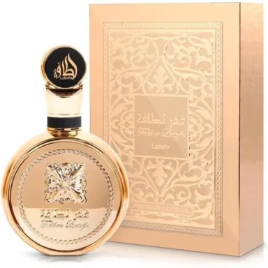 Frasco de perfume dorado con tapa negra y caja decorativa en tonos rosa y dorado.